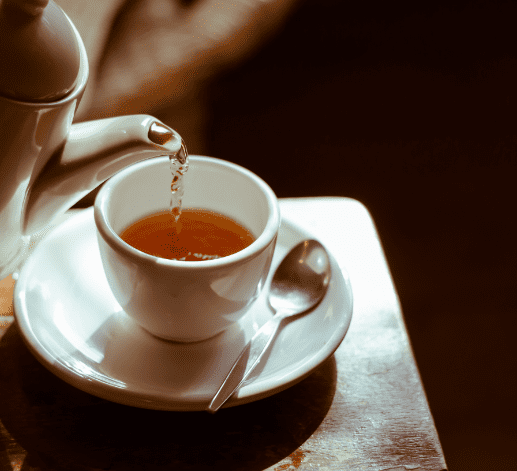 Plan sur une théière versant du thé dans une tasse à thé sur une table
